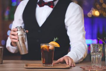 Male bartender making cocktail in pub