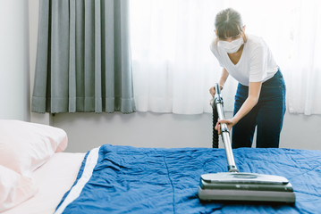Woman using vacuum cleaner with bed room in background.  With copy space and light leaks.