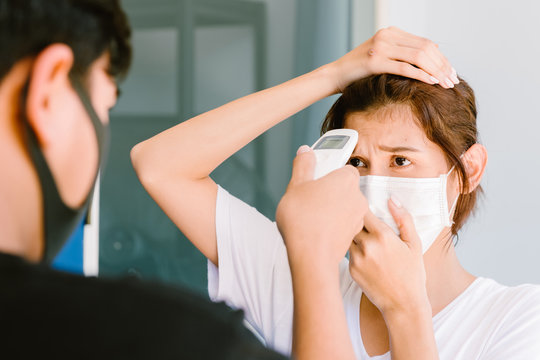 Woman got tempreture measure using digital infrared thermometer in front of building entrance. Health safety and security concept.