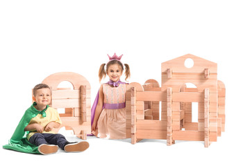 Little children in costumes playing with take-apart playhouse on white background