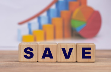 The concept of the word SAVE on cubes against the background of the graph