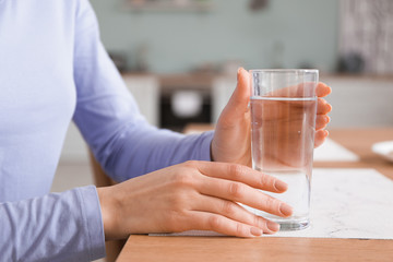 Beautiful young woman drinking water at home, closeup