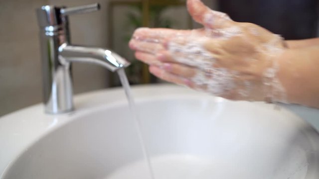 woman carefully washing hands with soap and sanitiser in home bathroom
