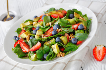 close-up of spinach avocado walnuts berries salad