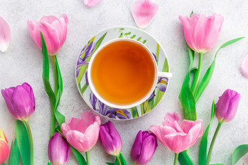 Fototapeta na wymiar A cup of tea with tulips on rose background