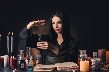 Female alchemist making potion on dark background