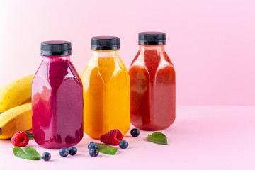 Colourful healthy smoothies and juices in bottles on color background with copy space.