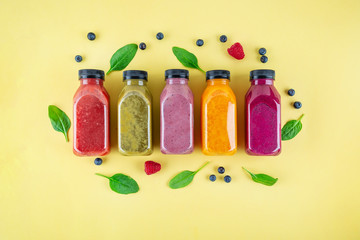 Colourful healthy smoothies and juices in bottles on color background with copy space.