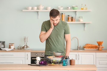 Shocked man looking at pile of dirty dishes on kitchen table