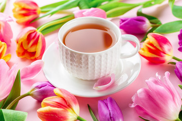 Obraz na płótnie Canvas A cup of tea with tulips on rose background