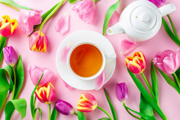 A cup of tea with tulips on rose background