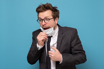 Young handsome man in medical mask has panic attack. He is afraid he is infected.