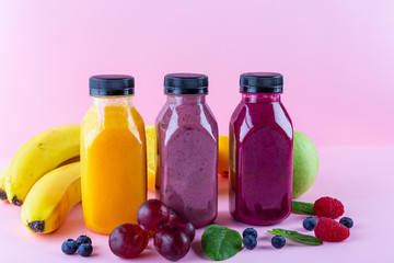 Colourful healthy smoothies and juices in bottles on color background with copy space.