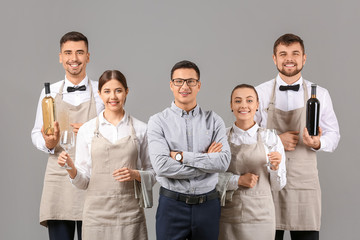 Group of waiters with teacher on grey background