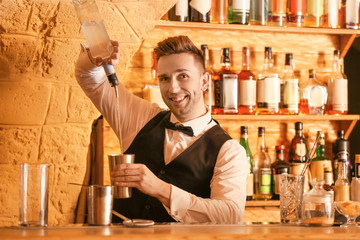 Male bartender making cocktail in pub