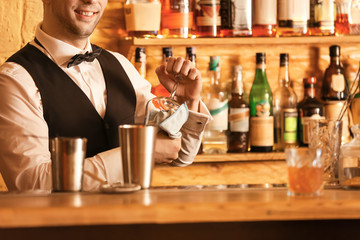 Male bartender wiping glass in pub