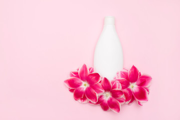 Natural herbal body lotion with flowers on pink background with a copy space