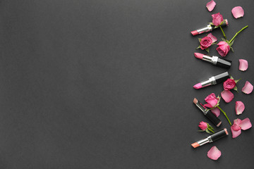 Different lipsticks and flowers on grey background