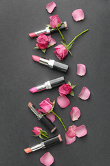 Obraz na płótnie Canvas Different lipsticks and flowers on grey background