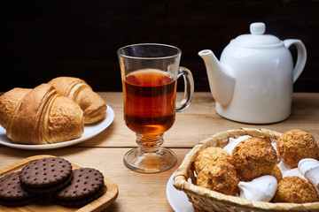 Hot tea put on table, drink breakfast in the morning day, breakfast with croissants and sweets on wooden table