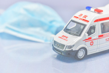 A surgical mask and ambulance model are placed on a white background. © hqrloveq