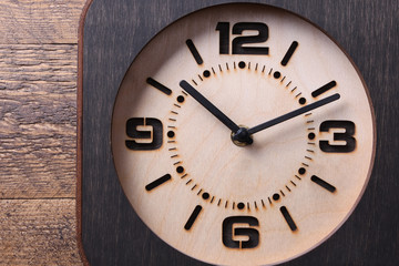 Wooden clock made in hand on wooden background. Close-up. Place for text.