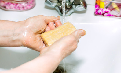 an elderly woman washes her hands holding soap in her hands, prevention of viral infections