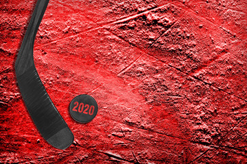 Black hockey stick and puck on red ice