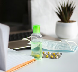 Remote work on the computer during quarantine, on the table a medical mask with antiseptic gel and medicine