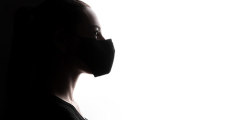 Backlight silhouette portrait of woman wearing mask during pandemic or air pollution. Covid-19 prevention
