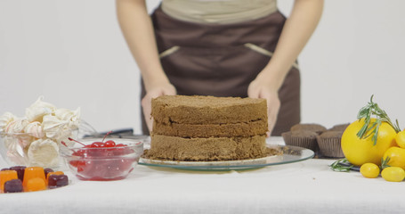 Step by step. Girl assembling a chocolate cake with bright colorful buttercream frosting