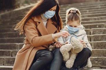 Family walks outside. Coronavirus theme. Mother with daughter. Toy in a mask.