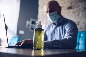 Man working at home and disinfect hand with antibacterial gel.