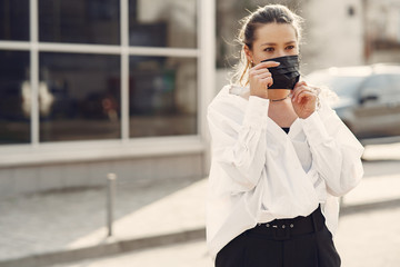 Fototapeta premium Woman in the city. Person in a mask. Coronavirus theme. Woman in a white shirt.