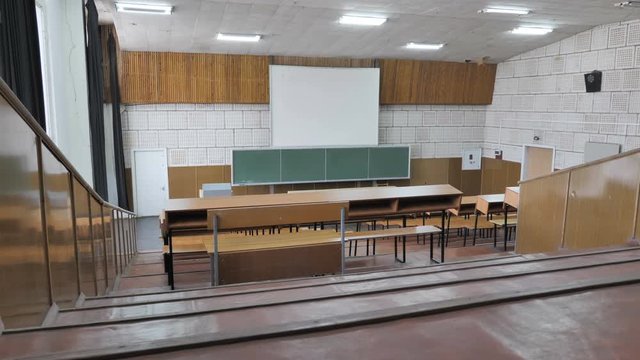 View from the last desk to the blackboard in empty lecture hall
