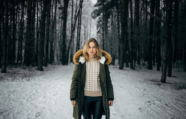 Young woman in jacket on background of snowy trees for walk in winter forest