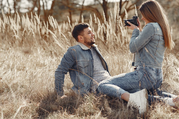 Naklejka na ściany i meble Woman in a jeans clothes. Couple in a spring field. Girl makes a photo to her boyfriend.