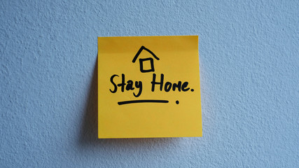 Writing attention message on memo post reminder 'Stay Home'