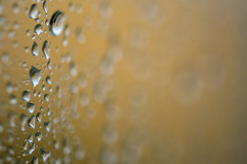 rain water droplets on a window with a golden background 