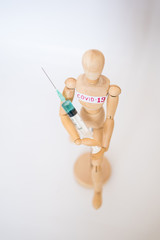 COVID-19 Pandemic Coronavirus concept ; Close-up of a wooden model man is carrying syringe. Corona virus vaccine on the way.