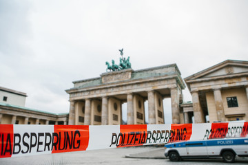 Police tape with the words police cordon in the background of the Brandenburg Gate in Berlin in Germany. The concept of banning visits to public places during the epidemic of the coronavirus COVID-19. © franz12