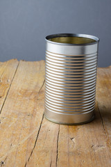 Top view of an empty can, to recycle, on rustic wooden table and gray background, vertically with copy space