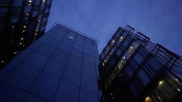 Office building exterior Glass facade detail Night city. Evening city skyline. slow  rollback shot