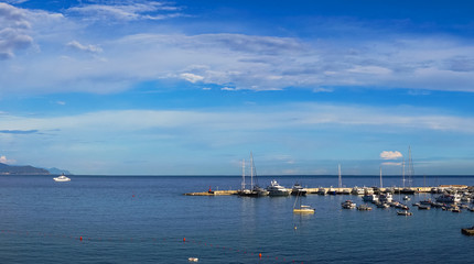 Wide panoramic view of luxury yachts and sailing boats moored in harbor of Santa Margherita Ligure, Italian Riviera. Beautiful mediterranean landscape with cloudy blue sky.