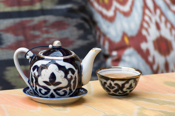 Traditional authentic uzbek teapot and teacup (piala) against traditional uzbek cushions....