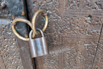 Old wooden door (with copper handles and padlock) of Mohammed Rakhim Khan Madrasah. Khiva, Uzbekistan.