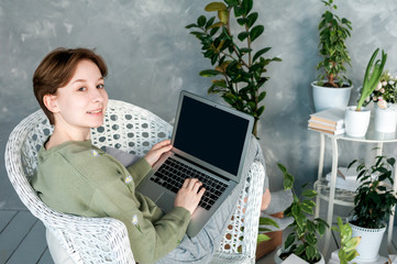 Smiling girl sits in chair in half-turned with laptop