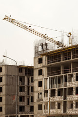  The construction of a multi-storey building. The crane. Concrete blocks. Metal carcass. Formwork. Large construction in the city