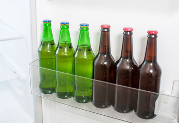 Green and brown glass beer bottles stand refrigerator door