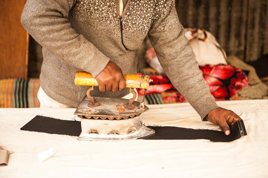 Clothes ironer. An ironer in the poor neighborhoods of New Delhi. Ironing clothes with an old cast iron.